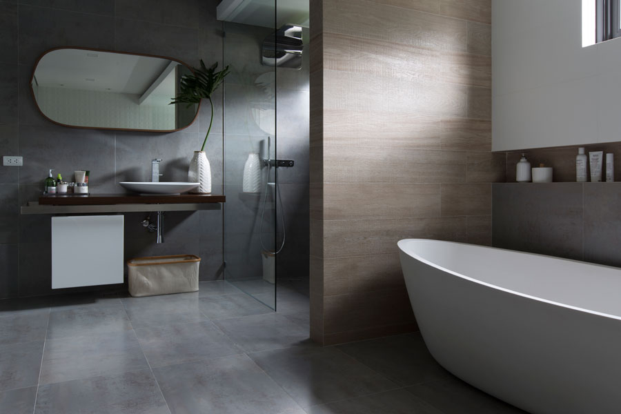 Heim Interiors and Porcelanosa worked wonders over the pre-renovation master bath, which was cramped and dark, by retiling the whole room and making use of glass dividers to let small pools of light softly illumine the interiors.